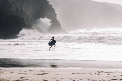 轮廓的人携带bodyboard海滨
